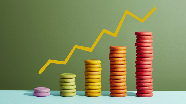 Increasing cash concept image, with multicolored round coins arranged under an increasing bar chart