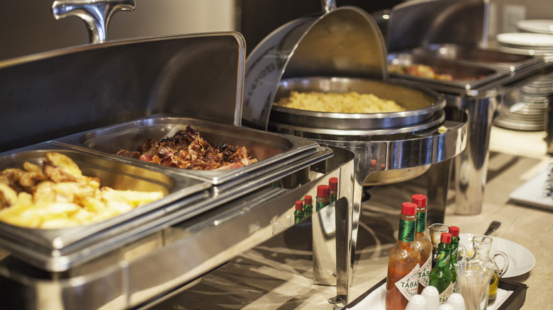 All-you-can-eat buffet food selection, with bottles of hot sauce and dressing in front of the food containers