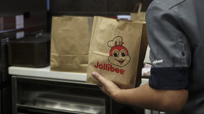 employee holding jollibee bag with bee mascot on it