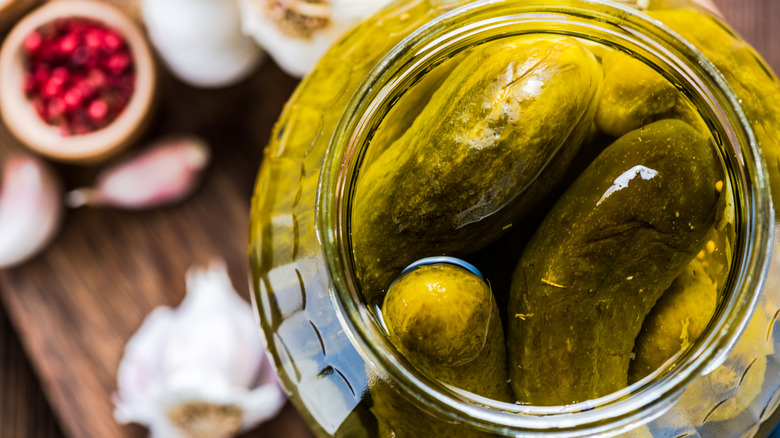 Open jar of green pickles soaking in brine