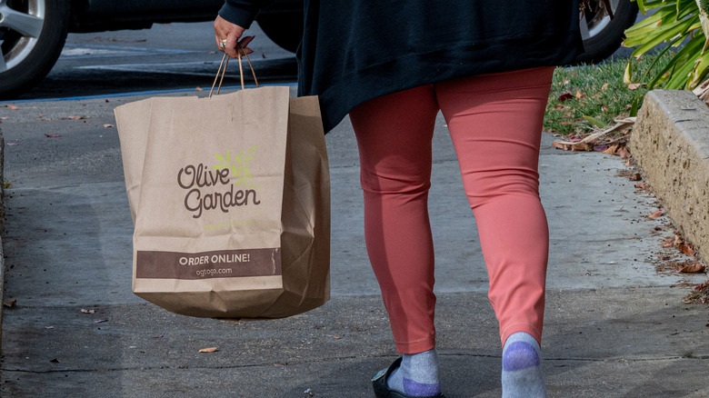 person walking away with olive garden bag