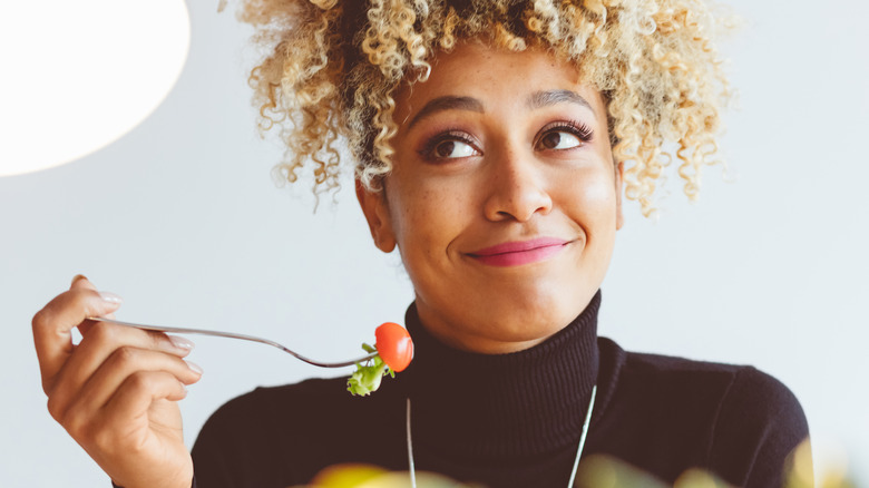 woman holding pieces of salad on fork