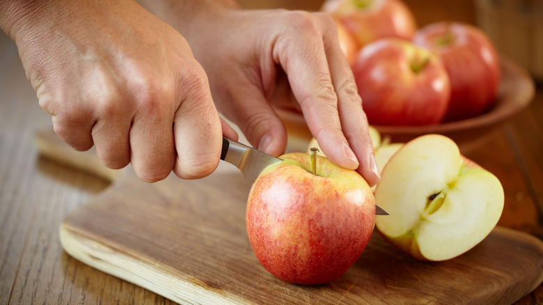 hands slicing apples on cutting board