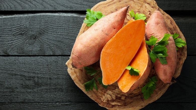 Halved sweet potatoes on wooden board