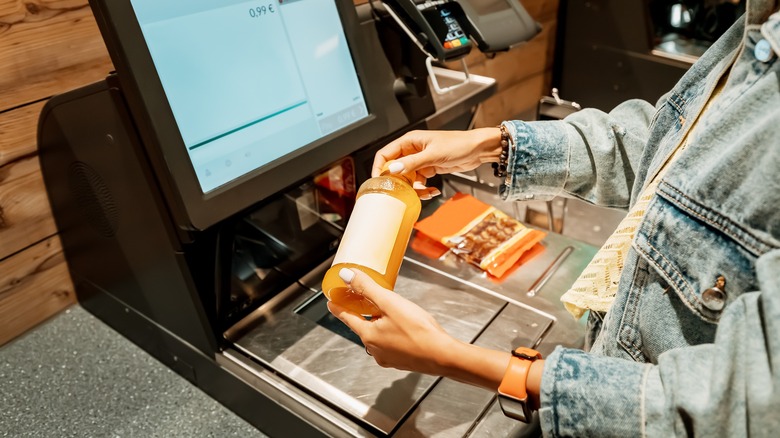 woman holds juice at self checkout