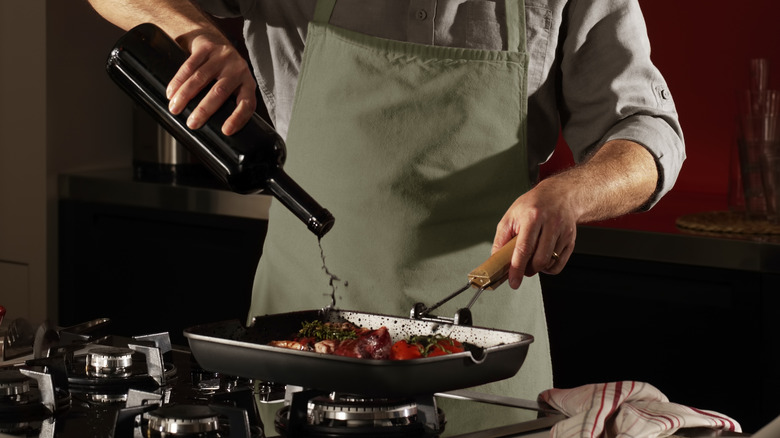 chef cooking with red wine in pan