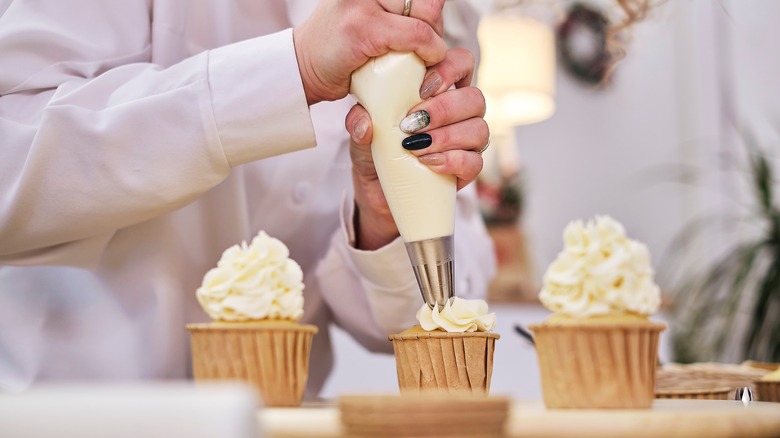 Cupcakes being topped with frosting