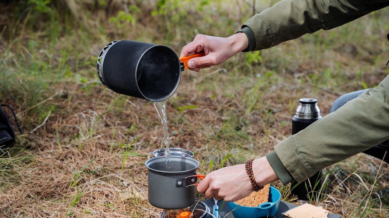 Person pouring water into a pot outdoors