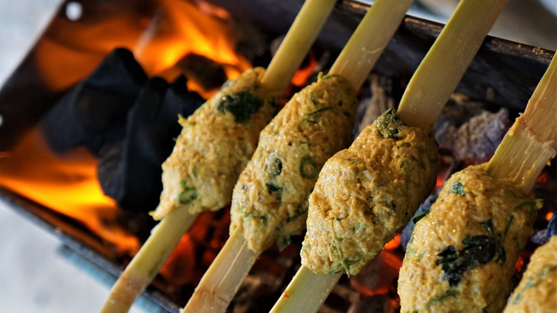 Sugarcane skewers with minced meat on the grill