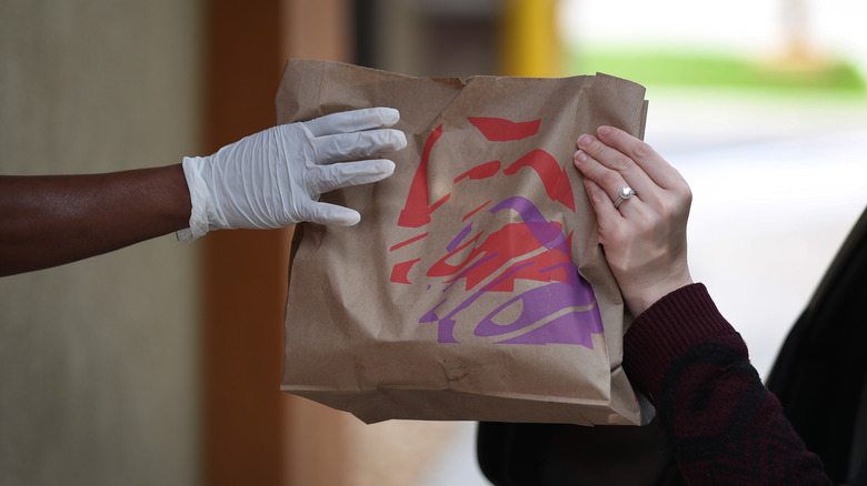 bag with taco bell logo being passed to customer at drive thru