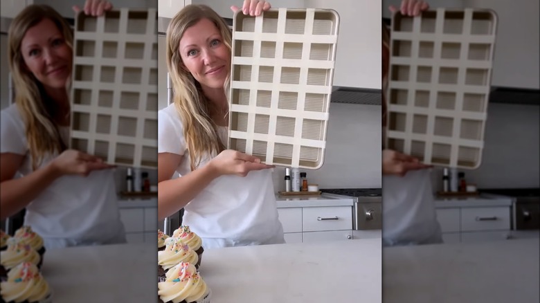 person holding up tray with tape grid for cupcakes