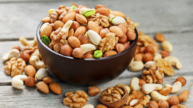 Black bowl of mixed nuts on slatted wooden surface