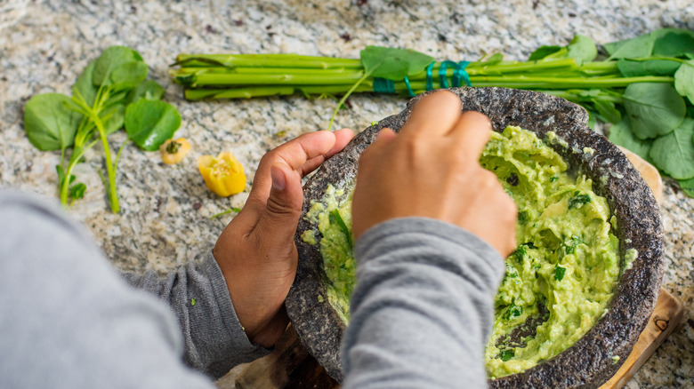 someone making guacamole in a molcajete