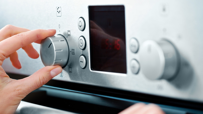 Hand turning an oven knob