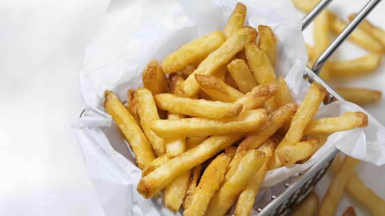 Golden french fries in a wire frying basket