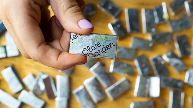 Fingers hold one mint over several others