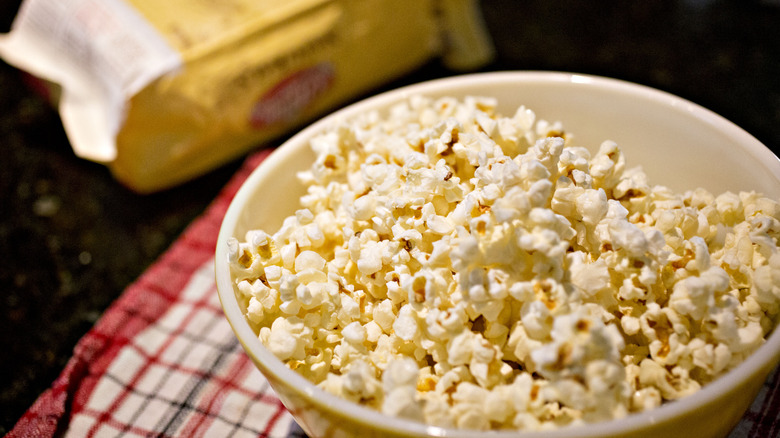 bowl of popcorn with a microwave bag in the background