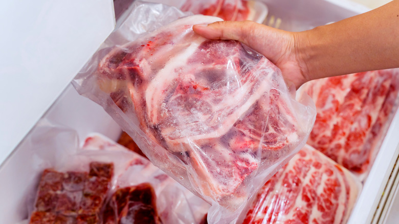 Hand removing meat from freezer