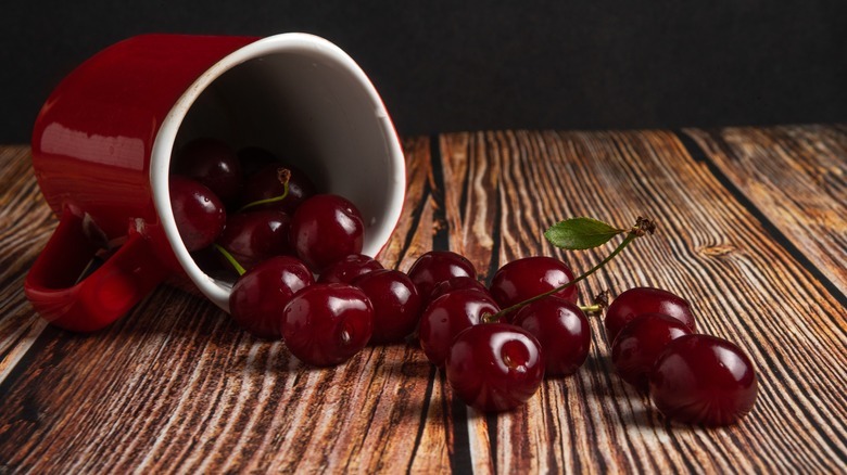 whole fresh cherries spilling out of overturned mug