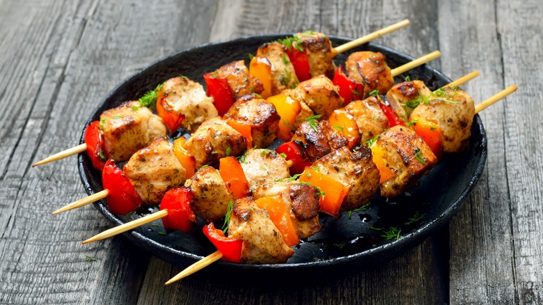 Chicken skewers on black plate