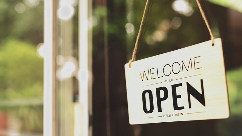 Business sign that reads "welcome, we are open"