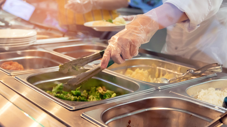 Serving staff grabbing food with serving utensils