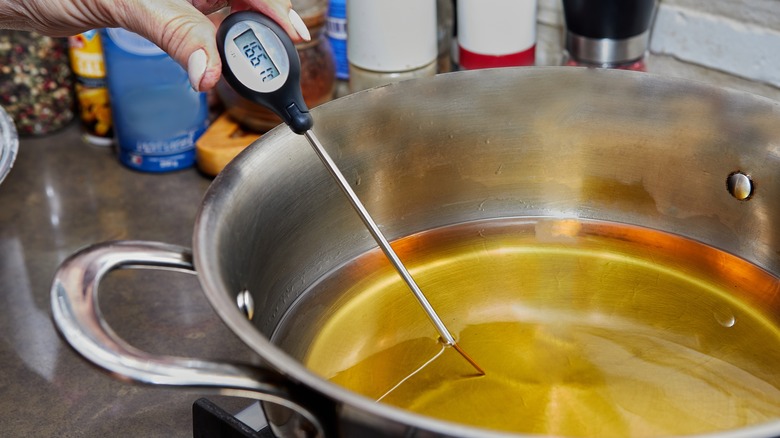 Chef measuring temperature of heated oil