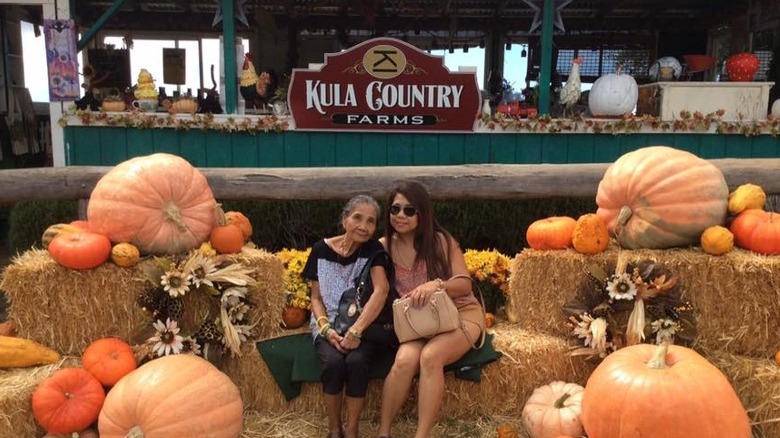 Two women sitting by pumpkins