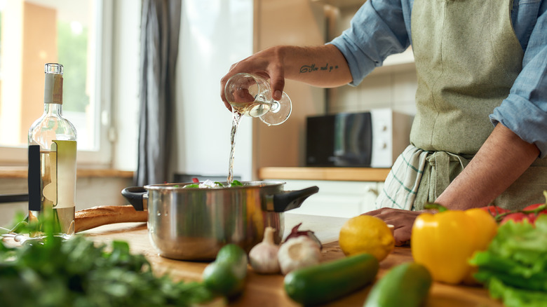 Cook adding wine to pot