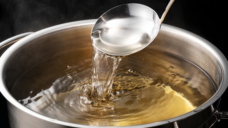 Ladle pouring water into large pot