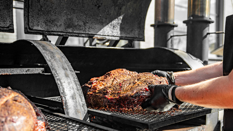 Person cooking meat in smoker