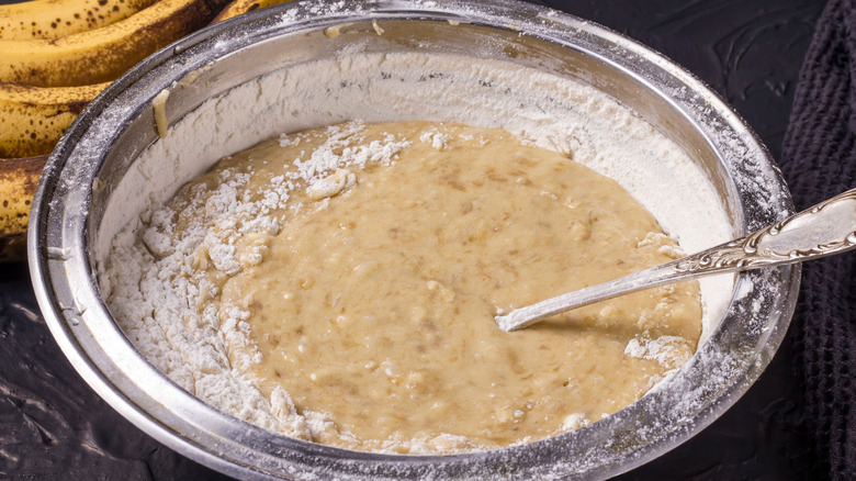 Mixing muffin batter in bowl with bananas