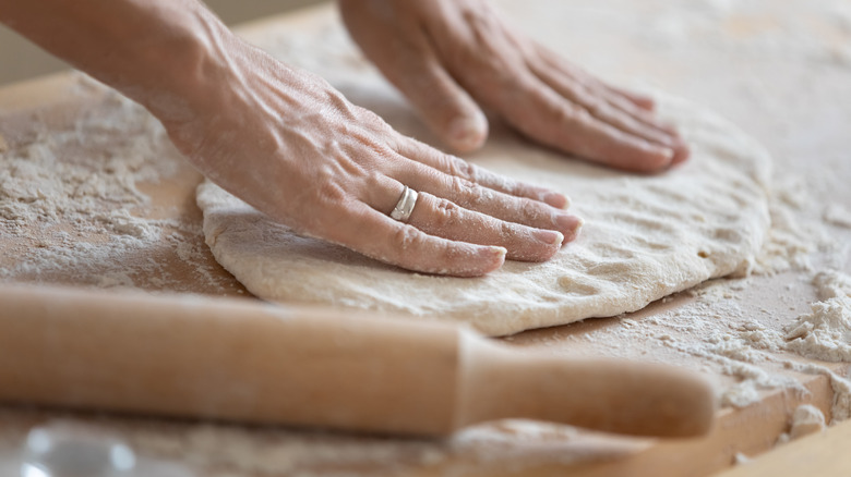 Pressing pie dough on floured surface