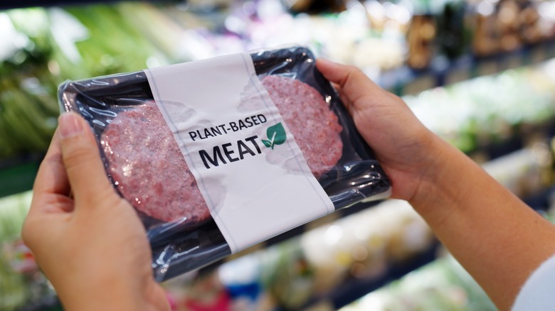 shopper holding plant-based meat package in grocery store