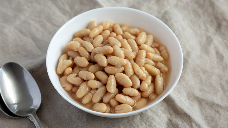 Tuscan white beans in a bowl next to a spoon.