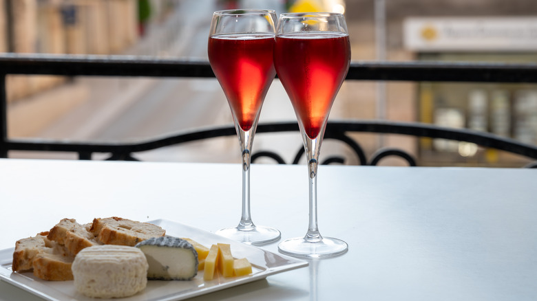 Kir cocktails side by side with cheese and bread on a plate