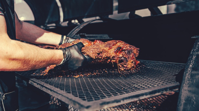 Person handling brisket on barbecue