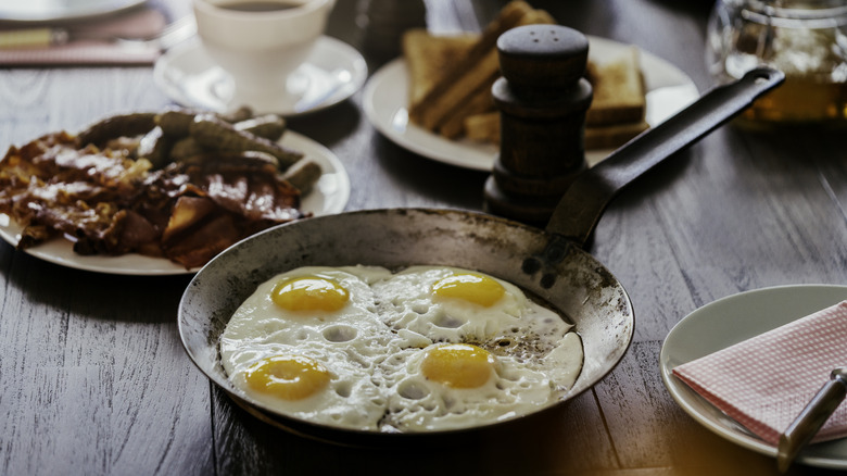 Four fried eggs in a skillet on the breakfast table