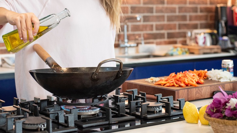 woman adding oil to wok