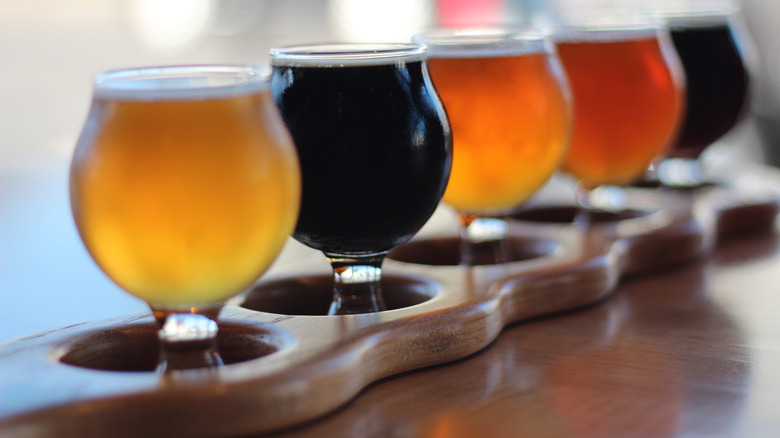 A flight of various types of beer in a wood stand