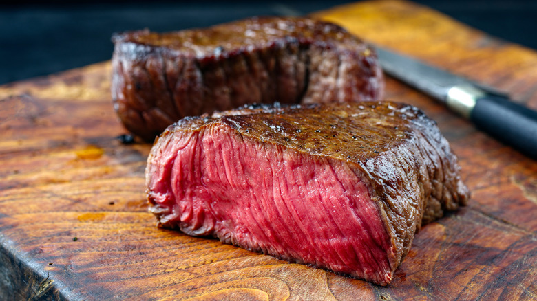 Blue steak sliced down the middle, sitting on wooden board