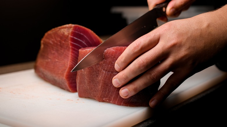 person slicing raw tuna