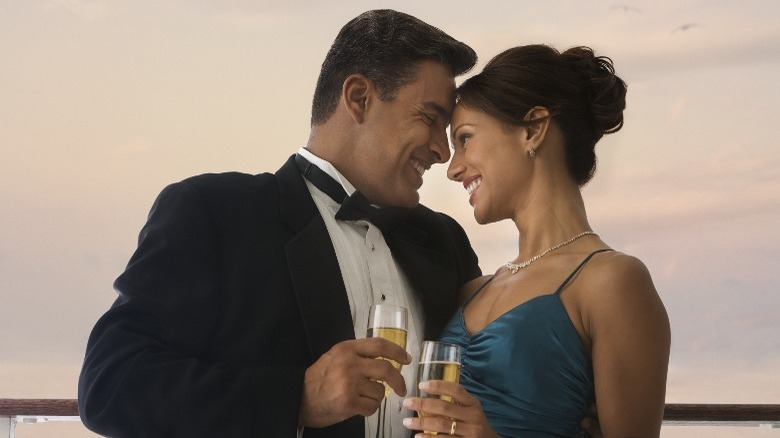 Fancy couple holding champagne on ship