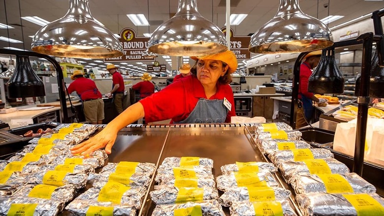 Woman putting Buc-ee's burritos on display