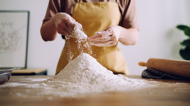 Woman sprinkling flour on counter