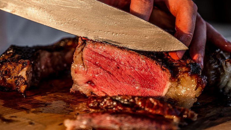 knife cutting into thick steak 