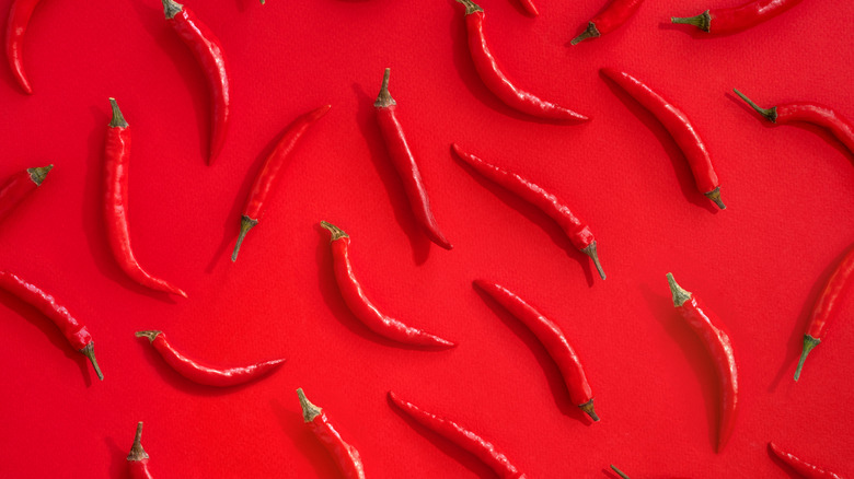 Red hot chili peppers arranged in pattern against red background