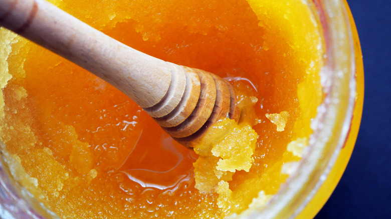 Crystallized honey in jar with honey dipper sitting in it