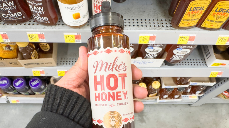 Person holding bottle of Mike's Hot Honey in supermarket