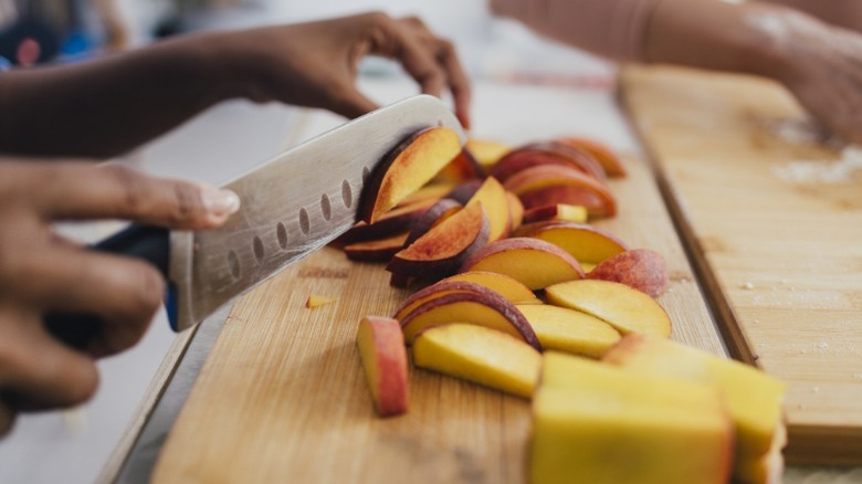 person slicing peaches